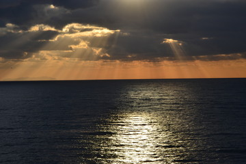 Fototapeta na wymiar sonnenuntergang über dem Meer, Sonnenstrahlen zwischen den Wolken