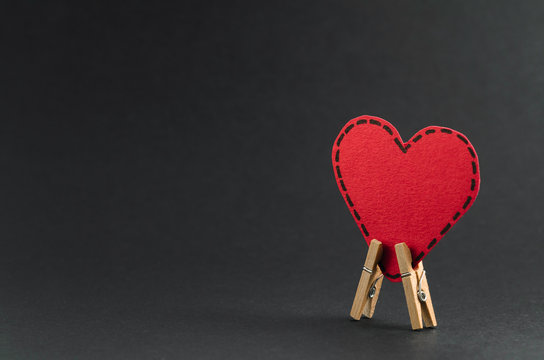 Red heart on the clothespin with the greeting happy Valentines day on dark background.