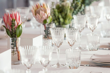 Table decorations for wedding with Protea flowers. Glassware reflecting in the sun.