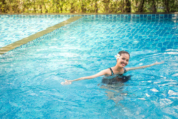 Naklejka premium Smiling portrait of beautiful woman in swimming pool,Beautiful young woman relaxing in spa swimming pool.