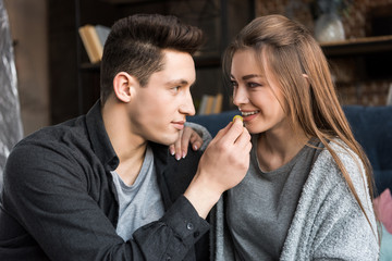 boyfriend feeding happy girlfriend with grape
