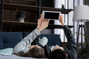couple lying on bed and looking at tablet