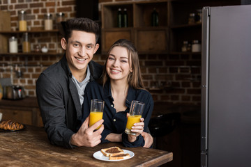 smiling couple with orange juice looking at camera