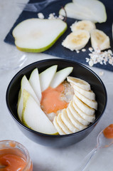 Breakfast oatmeal bowl with bananas, peares and honey. Healthy food.
