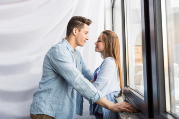 happy couple looking at each other near window