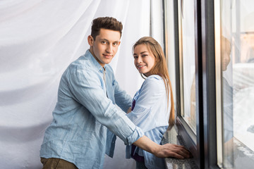 happy couple near window looking at camera