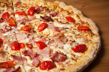 Delicious Italian pizza with ham, cherry tomatoes and parmesan on wooden table. Top view
