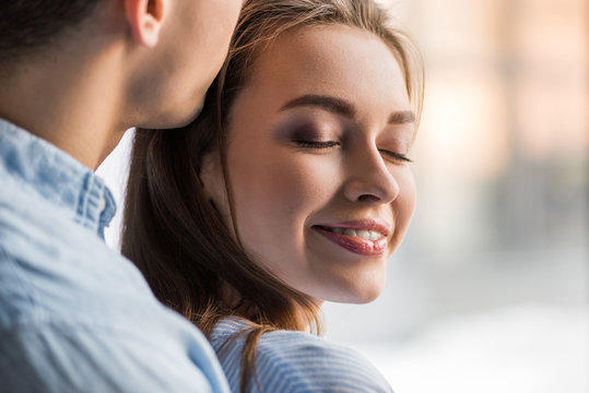 cropped image of boyfriend kissing happy girlfriend