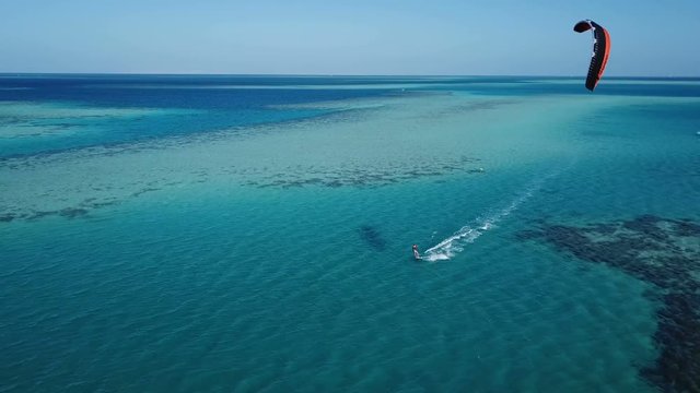 Aerial view young man kite surfing in tropical blue ocean