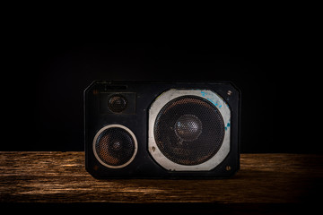 Vintage speaker on wooden table with black background