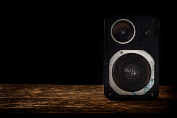 Vintage speaker on wooden table with black background