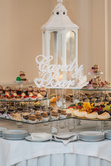 Candybar in a restaurant. Decorated white table fool of sweet pastry