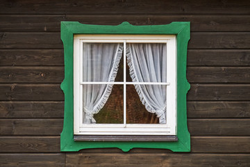 Aged wooden window with green frame on old german wooden hut