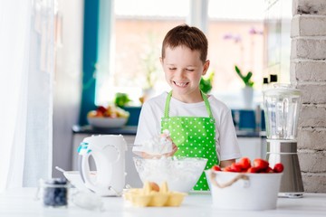 Obraz na płótnie Canvas Happy child boy trying sweet dough and preparing a cake.