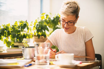 Beautiful blond female with short hair studying in the public library with a cup of coffee in front.