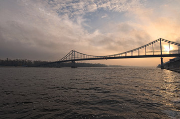 Pedestrian bridge to the Trukhanov island in Kyiv through the Dnipro River in the sunrise. Winter morning. Ukraine. Selective focus with wide angle lens