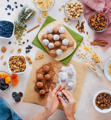 Female hands making candies from dried fruits, nuts and chickpeas