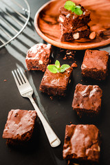 Homemade chocolate brownies on a wooden plate close-up, top view