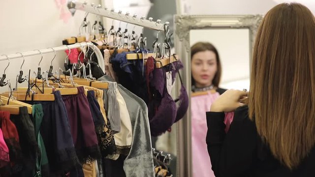 Woman is shopping, choosing pajamas in boutique
