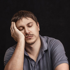 A man with closed eyes leans on his arm