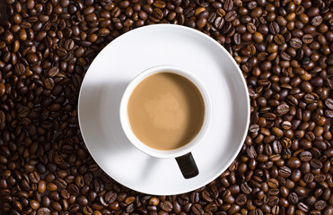 Cup of coffee shot from above on coffee bean table.