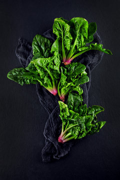 freshly harvested spinach on dark kitchen plate and napkin can be used as background