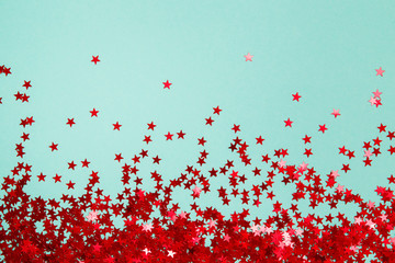 Confetti. Frame made of colored red star confetti front of blue background. Copy space