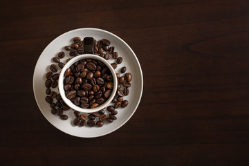 Freshly roasted coffee beans in coffee cup on wooden table - coffee shop scene.