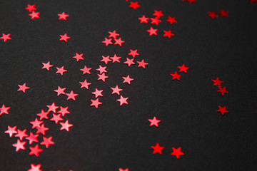 Confetti. Frame made of colored red star confetti front of black background. Copy space