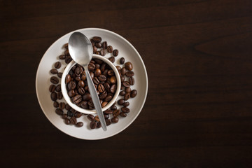 Freshly roasted coffee beans in coffee cup on wooden table - coffee shop scene.