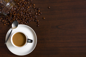 Cup of coffee from above, lay flat image, with coffee beans on wood table.