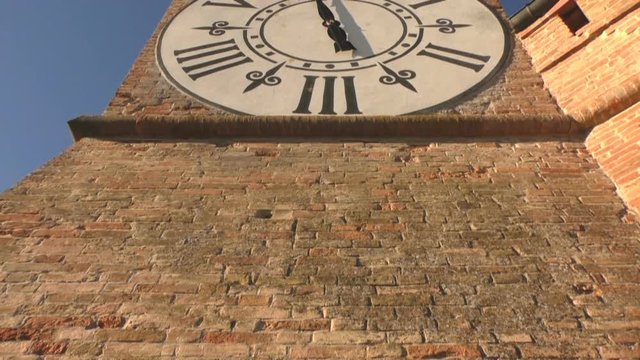 Medieval tower in a castle with a nice white clock, filmed from bottom to top, low angle.