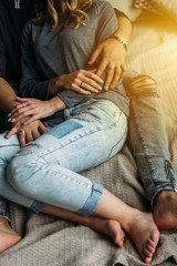 Cropped view of youngcouple embracing and relaxing on bed at home. Vintage casual look. Torn blue jeans. Winter time