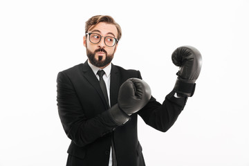 Portrait of courageous business man in suit and eyeglasses boxing in black gloves, isolated over white background