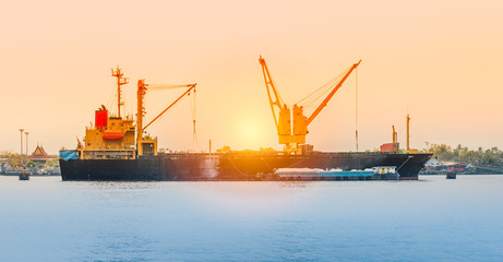 Fototapeta premium Vessel working with crane on a river with sunset lighting.