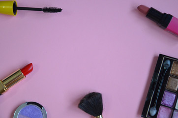 Make up bag, brush with cosmetics on pink background