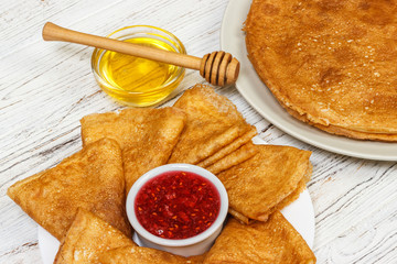 pancakes with honey and jam on wooden background