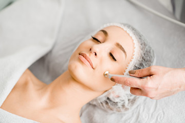 Young woman during the facial treatment procedure in the cosmetology office