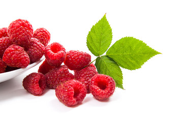 Small plate with ripe raspberries and green leaf isolated on white background.