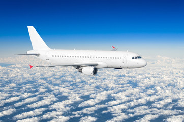 Passenger plane fly on a train above clouds and blue sky.