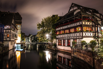 Fototapeta premium Picturesque view of traditional Alsatian half-timbered houses with mirror reflections in Petite France during night. Strasbourg, Alsace, France.