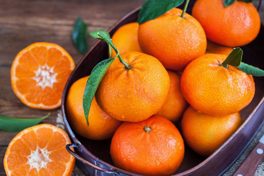 Fresh tangerines with leaves on  wooden table