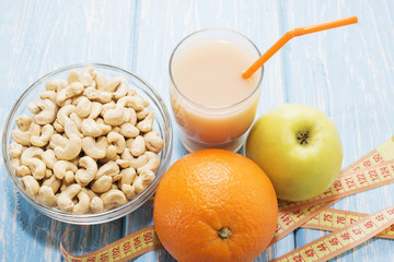healthy breakfast. The cashew nuts in a white bowl. Green Apple, orange, banana. Flat top view