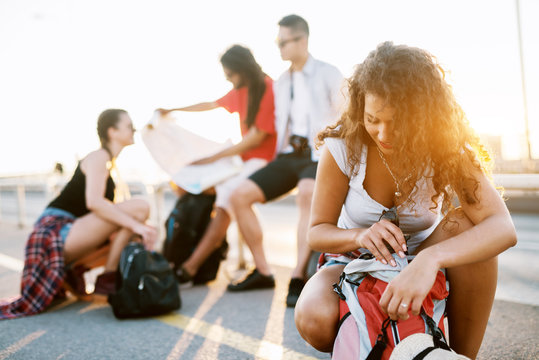 Young students on a tourist tour in a city taking a break to look for directions and repack