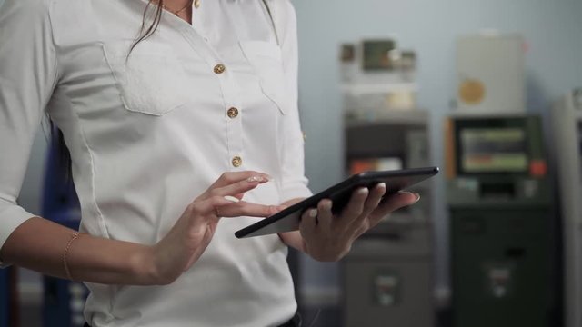 Businesswoman use digital tablet on ATM background, bank work, business woman withdrawal