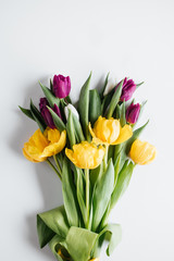 top view of bouquet of purple and yellow tulips on white