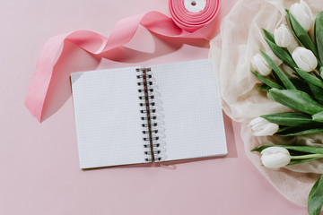 top view of notepad, pink ribbon and white tulips for international womens day