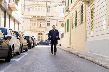 The man goes along streets of Malta, business thoughts