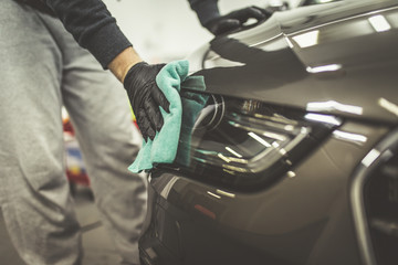 A man cleaning car with microfiber cloth, car detailing (or valeting) concept. Selective focus. 