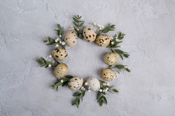 Fototapeta na wymiar Circle border for easter card or invitation. Easter wreath with easter quail and leaf sprigs of eucalyptus. On a gray concrete background with place for text.